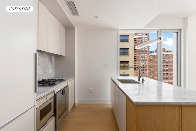 250 E 25th St Unit 9D, New York City, NY 10010 - kitchen featuring white fridge, modern cabinets, oven, light wood finished floors, and tasteful backsplash