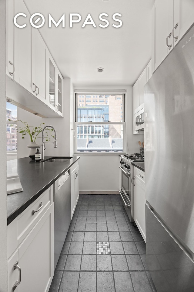 350 W 14th St Unit 6D, New York City, NY 10014 - kitchen with appliances with stainless steel finishes, dark countertops, white cabinets, glass insert cabinets, and recessed lighting