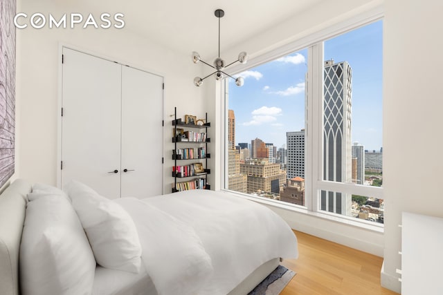 15 E 30th St Unit 30C, New York City, NY 10016 - bedroom with light wood-type flooring, a closet, a chandelier, and a view of city