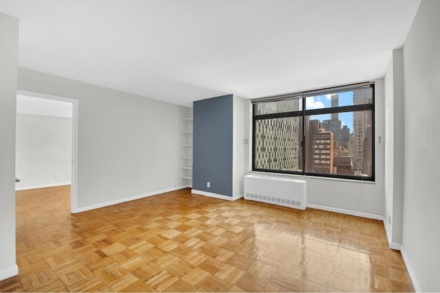 400 E 70th St Unit 1208, New York City, NY 10021 - unfurnished room with radiator heating unit, a view of city, and built in shelves