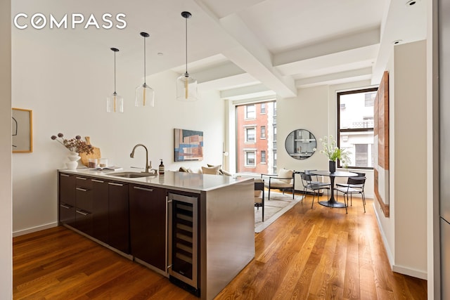 76 Madison Ave Unit 8C, New York City, NY 10016 - kitchen with beverage cooler, dark brown cabinets, light wood-style flooring, modern cabinets, and light countertops