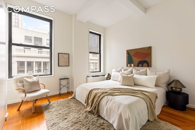 76 Madison Ave Unit 8C, New York City, NY 10016 - bedroom featuring beamed ceiling, wood finished floors, and an AC wall unit