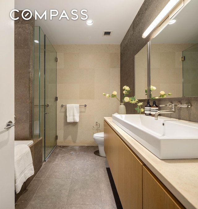 76 Madison Ave Unit 8C, New York City, NY 10016 - full bathroom featuring tile walls, vanity, a stall shower, and tile patterned floors