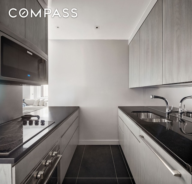 58 W 58th St Unit 19A, New York City, NY 10019 - kitchen with appliances with stainless steel finishes, dark countertops, dark tile patterned floors, and modern cabinets