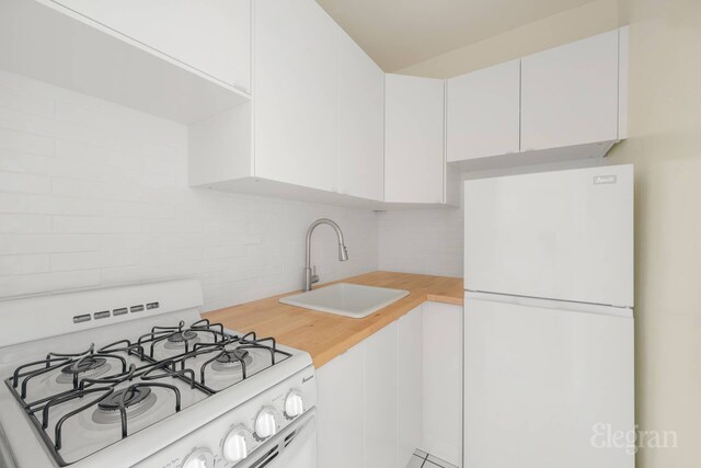 25 W 13th St Unit 6Kn, New York City, NY 10011 - kitchen with white appliances, decorative backsplash, and white cabinetry