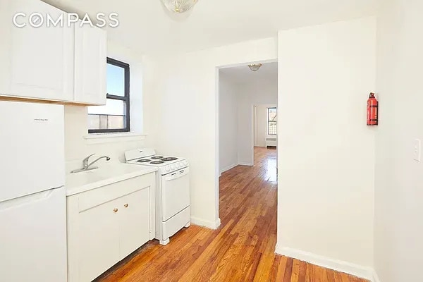 506 W 145th St Unit 4D, New York City, NY 10031 - kitchen with white appliances, light wood-style flooring, white cabinetry, and light countertops