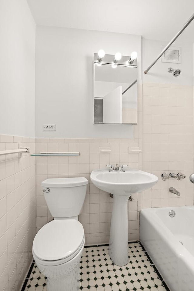 66 Madison Ave Unit 2De, New York City, NY 10016 - full bathroom featuring tile walls, shower / washtub combination, a wainscoted wall, and tile patterned flooring