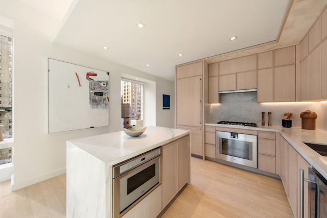 138 E 50th St Unit 26A, New York City, NY 10022 - kitchen with stainless steel appliances, modern cabinets, tasteful backsplash, light countertops, and light brown cabinets