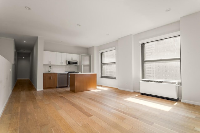 20 W St Unit 18F, New York City, NY 10004 - kitchen with appliances with stainless steel finishes, light countertops, white cabinets, light wood-type flooring, and recessed lighting
