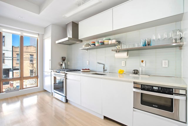 210 Jackson St Unit 2, New York City, NY 11211 - kitchen with stainless steel appliances, wall chimney exhaust hood, backsplash, light wood finished floors, and open shelves