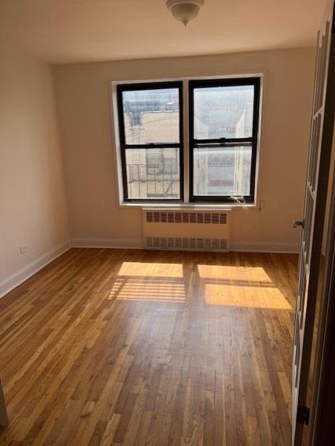 282 E 35th St Unit 4W, New York City, NY 11203 - empty room featuring radiator heating unit, plenty of natural light, and wood finished floors