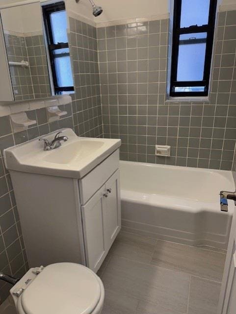 282 E 35th St Unit 4W, New York City, NY 11203 - bathroom featuring vanity, tile patterned flooring, tile walls, and shower / washtub combination