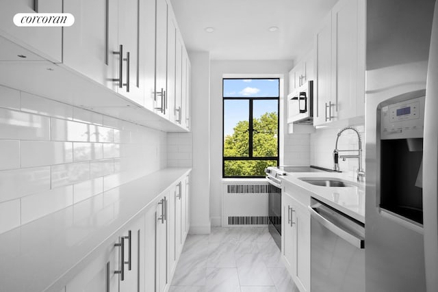 100 Riverside Dr Unit 7B, New York City, NY 10024 - kitchen with appliances with stainless steel finishes, radiator heating unit, light countertops, light marble finish floors, and white cabinetry