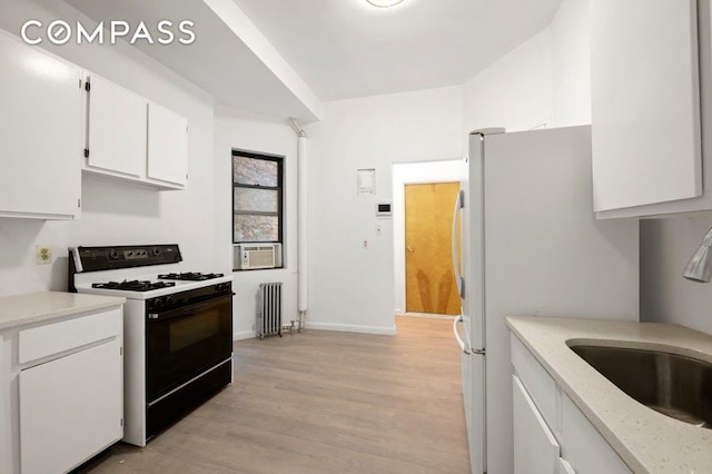 312 W 49th St Unit 1Rw, New York City, NY 10019 - kitchen featuring range with gas cooktop, radiator, white cabinetry, light wood-style flooring, and light stone counters