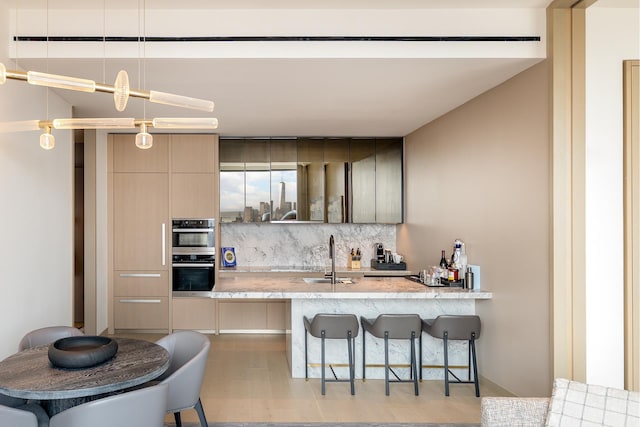 25 W 28th St Unit Ph40C, New York City, NY 10001 - kitchen featuring decorative backsplash, a kitchen bar, modern cabinets, double oven, and a peninsula