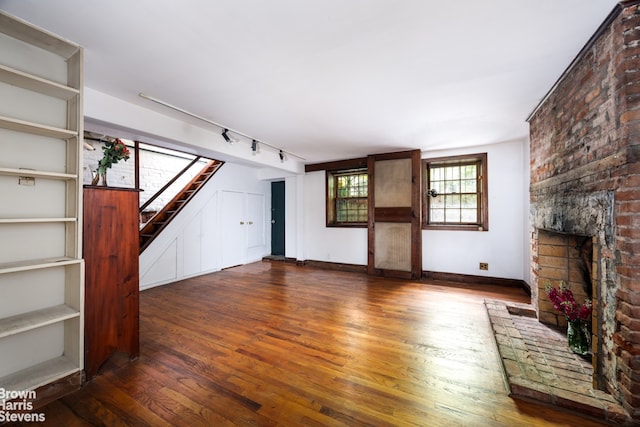 47 King St Unit 2, New York City, NY 10014 - unfurnished living room featuring hardwood / wood-style flooring, stairs, a fireplace, and rail lighting