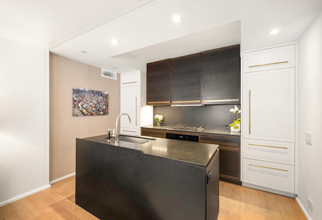 345 W 14th St Unit 5A, New York City, NY 10014 - kitchen featuring dark countertops, light wood-type flooring, a center island with sink, dark brown cabinetry, and recessed lighting