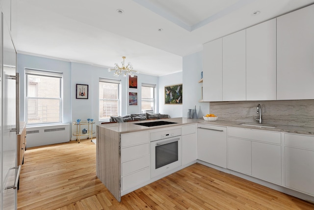 26 Gramercy Park S Unit 8Cd, New York City, NY 10003 - kitchen with white appliances, a peninsula, a chandelier, white cabinetry, and tasteful backsplash