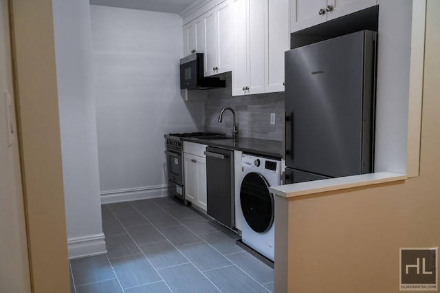 160 E 3rd St Unit 2F, New York City, NY 10009 - kitchen featuring freestanding refrigerator, washer / dryer, dishwasher, dark tile patterned flooring, and white cabinets