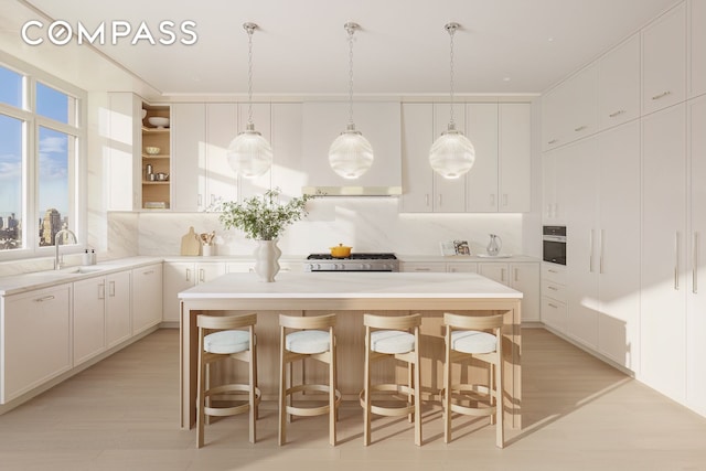 255 E 77th St Unit 3D, New York City, NY 10075 - kitchen featuring a kitchen island, white cabinetry, light countertops, and a kitchen breakfast bar