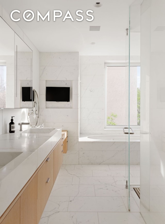 950 5th Ave Unit 3/4, New York City, NY 10075 - bathroom featuring a garden tub, double vanity, marble look tiles, and a marble finish shower