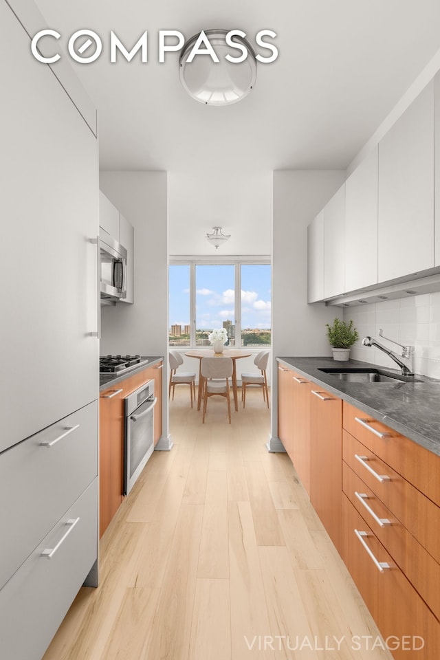 100 Riverside Blvd Unit 29C, New York City, NY 10069 - kitchen with appliances with stainless steel finishes, modern cabinets, light wood finished floors, white cabinetry, and dark stone countertops