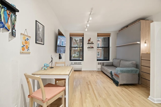 315 W 55th St Unit 1-D, New York City, NY 10019 - dining area featuring track lighting, radiator, and light wood-style flooring