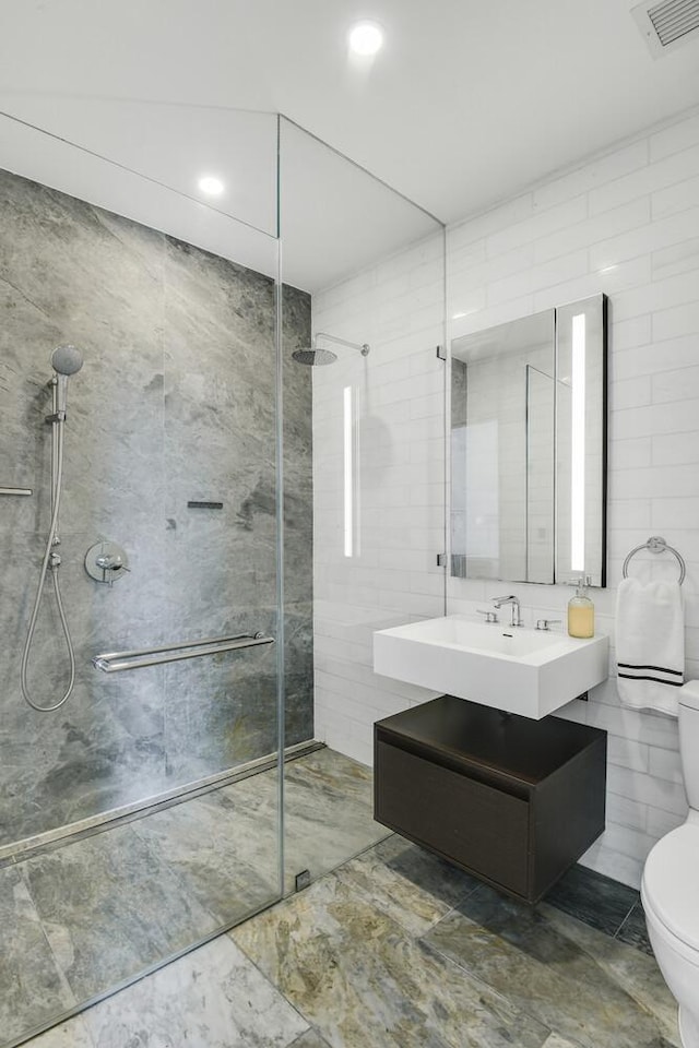 287 E Houston St Unit 4B, New York City, NY 10002 - full bath with a tile shower, tile walls, vanity, marble finish flooring, and recessed lighting