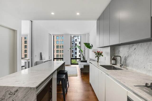287 E Houston St Unit 4B, New York City, NY 10002 - kitchen with dark wood finished floors, backsplash, light stone counters, a center island, and recessed lighting