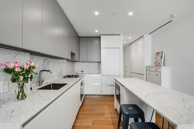 287 E Houston St Unit 4B, New York City, NY 10002 - kitchen featuring modern cabinets, light wood-type flooring, stainless steel appliances, decorative backsplash, and a kitchen island