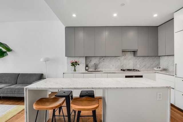 287 E Houston St Unit 4B, New York City, NY 10002 - kitchen with gray cabinets, a breakfast bar area, tasteful backsplash, and recessed lighting