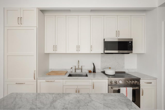 186 Clinton Ave Unit 4B, New York City, NY 11205 - kitchen featuring appliances with stainless steel finishes, light stone counters, white cabinetry, and backsplash