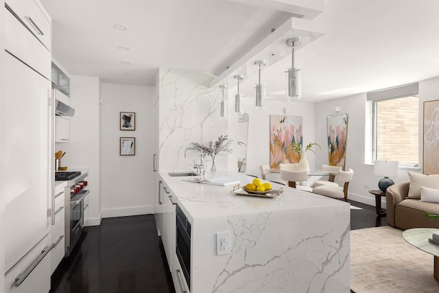 1965 Broadway Unit 8K, New York City, NY 10023 - kitchen with high quality appliances, under cabinet range hood, light stone counters, dark wood finished floors, and decorative light fixtures