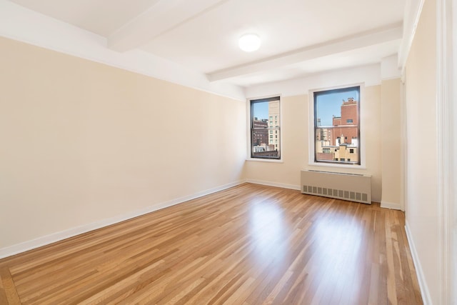 205 E 78th St Unit 14C, New York City, NY 10021 - spare room featuring radiator heating unit, beam ceiling, and light wood-style floors
