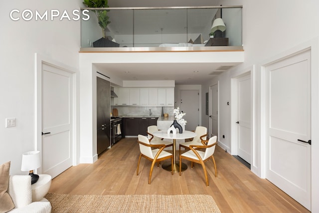 172 N 10th St Unit 3D, New York City, NY 11211 - dining room featuring light wood-style floors and a towering ceiling