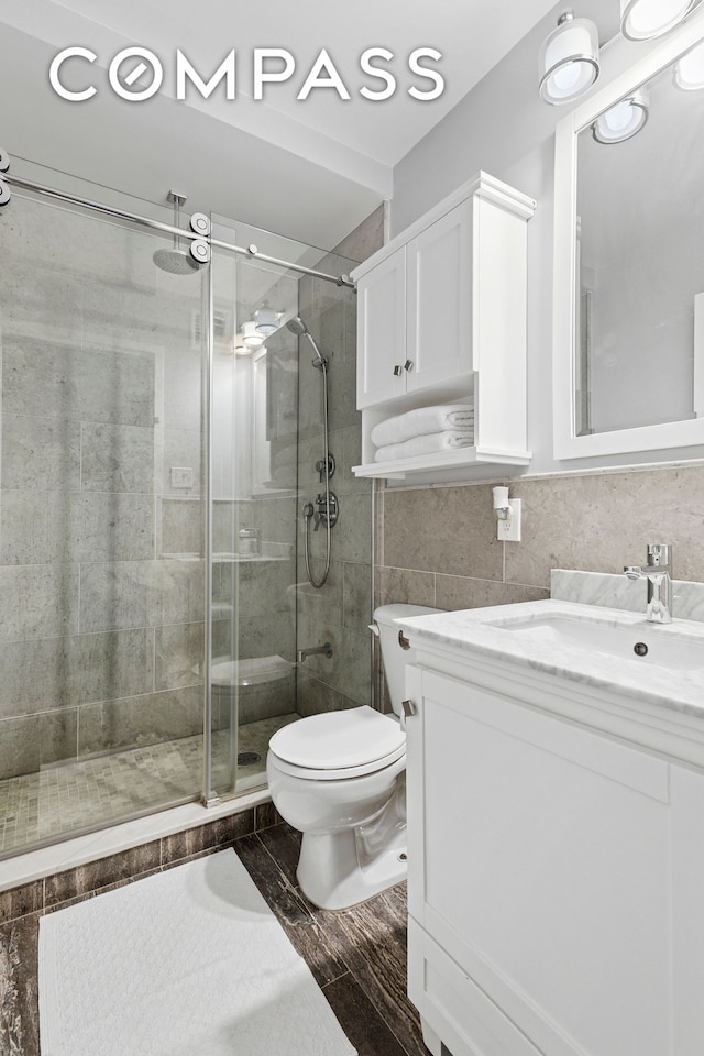 200 E 89th St Unit 34Cd, New York City, NY 10128 - bathroom with vanity, a shower stall, wood finished floors, and tile walls