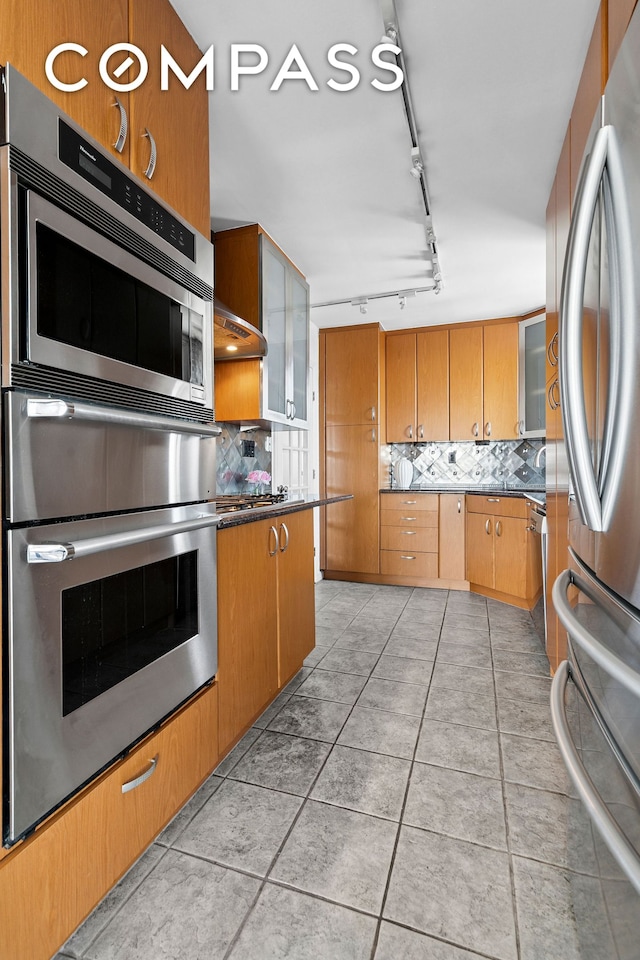 200 E 89th St Unit 34Cd, New York City, NY 10128 - kitchen featuring stainless steel appliances, decorative backsplash, rail lighting, and glass insert cabinets