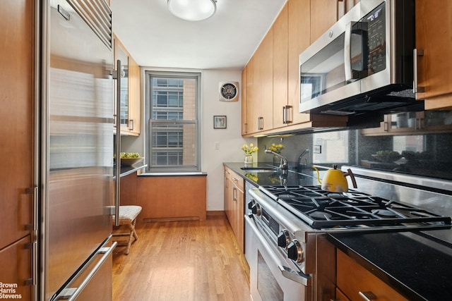 500 E 83rd St Unit 12C, New York City, NY 10028 - kitchen with stainless steel appliances, light wood-type flooring, decorative backsplash, and brown cabinetry