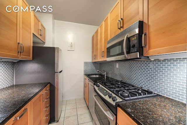 222 E 80th St Unit 1F, New York City, NY 10075 - kitchen featuring appliances with stainless steel finishes, tasteful backsplash, light tile patterned floors, and dark stone countertops