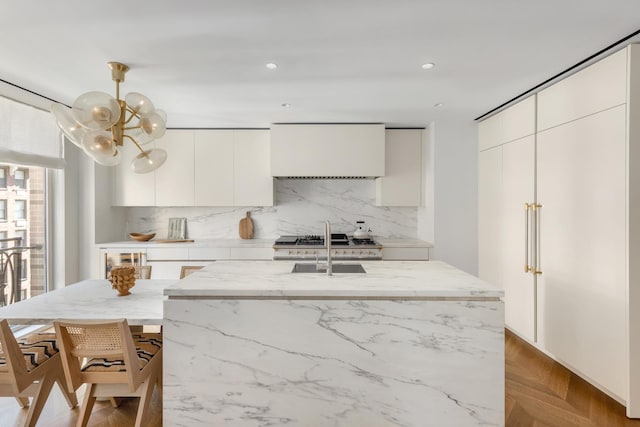 1228 Madison Ave Unit 4, New York City, NY 10128 - kitchen with modern cabinets, wall chimney exhaust hood, tasteful backsplash, light stone counters, and recessed lighting