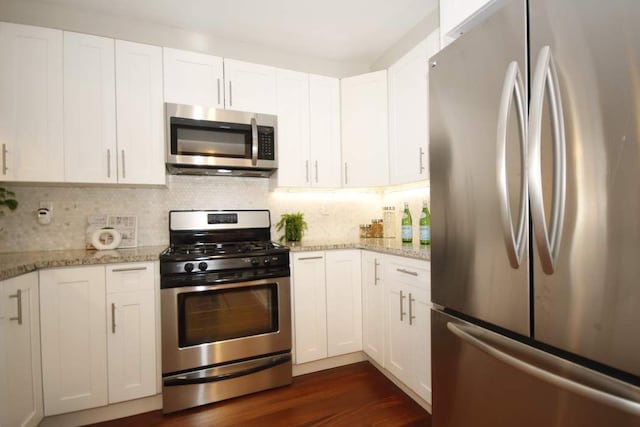 603 W 148th St Unit 3, New York City, NY 10031 - kitchen featuring stainless steel appliances, white cabinets, backsplash, light stone countertops, and dark wood-style floors