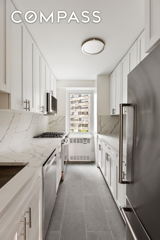 411 E 53rd St Unit 6L, New York City, NY 10022 - kitchen featuring stainless steel appliances, radiator heating unit, and white cabinetry