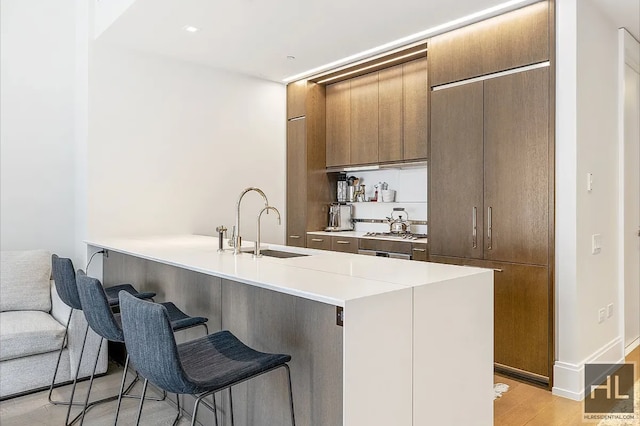 301 E 50th St Unit 5B, New York City, NY 10022 - kitchen featuring a kitchen breakfast bar, light countertops, range, modern cabinets, and light wood finished floors