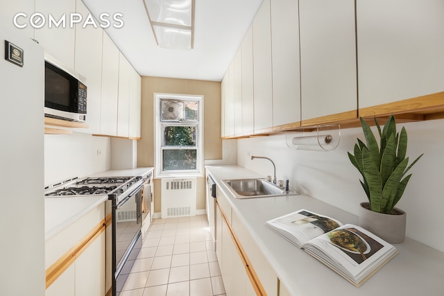 50 Sutton Pl S Unit 5E, New York City, NY 10022 - kitchen featuring stainless steel range with gas stovetop, radiator, light countertops, and light tile patterned flooring