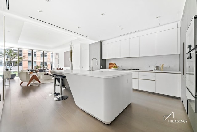 520 W 28th St Unit 7, New York City, NY 10001 - kitchen featuring floor to ceiling windows, modern cabinets, light countertops, light wood-style flooring, and white cabinetry