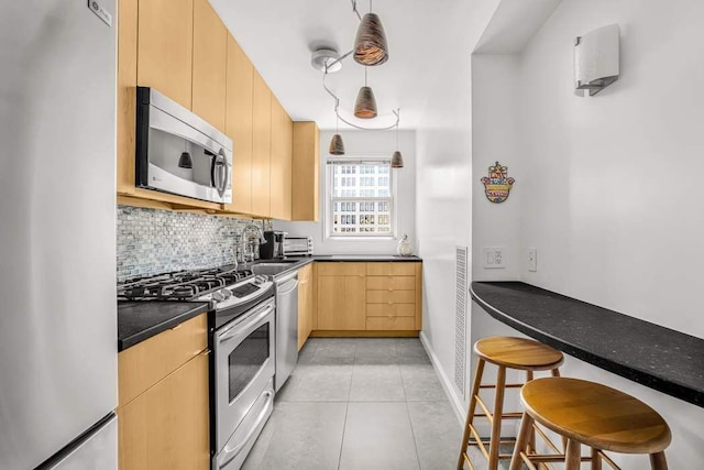 40 E 9th St Unit 9K, New York City, NY 10003 - kitchen featuring stainless steel appliances, light brown cabinetry, tasteful backsplash, light tile patterned floors, and dark countertops