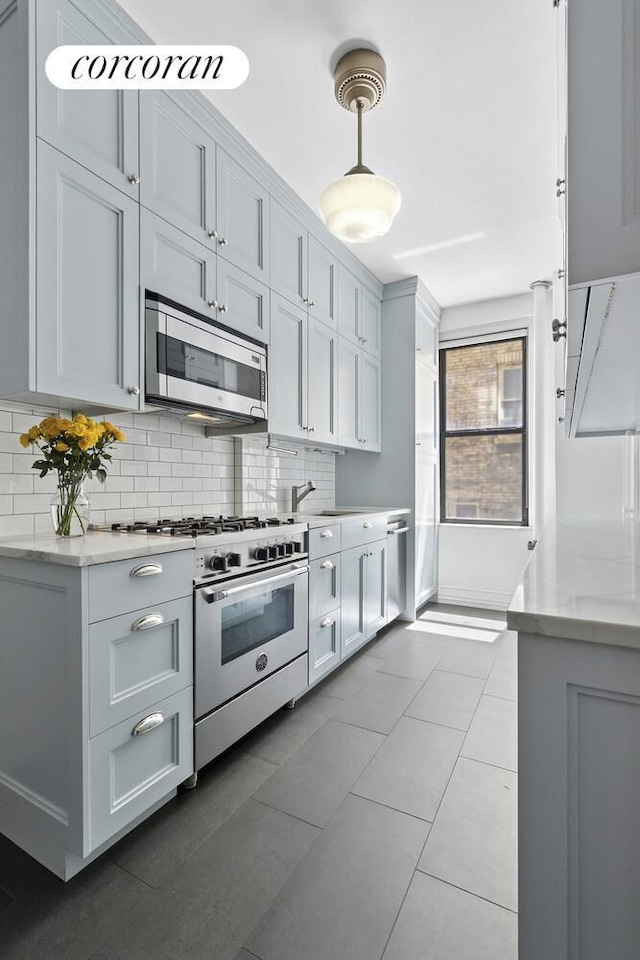 221 W 82nd St Unit 2B, New York City, NY 10024 - kitchen featuring appliances with stainless steel finishes, tasteful backsplash, hanging light fixtures, and light stone countertops