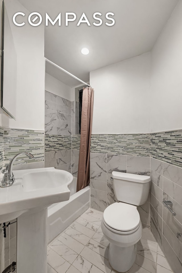 786 9th Ave Unit 2R, New York City, NY 10019 - bathroom featuring tile walls, shower / bath combo with shower curtain, wainscoting, marble finish floors, and recessed lighting