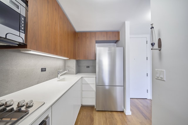 515 E 72nd St Unit 9N, New York City, NY 10021 - kitchen with stainless steel appliances, brown cabinets, light countertops, tasteful backsplash, and light wood finished floors