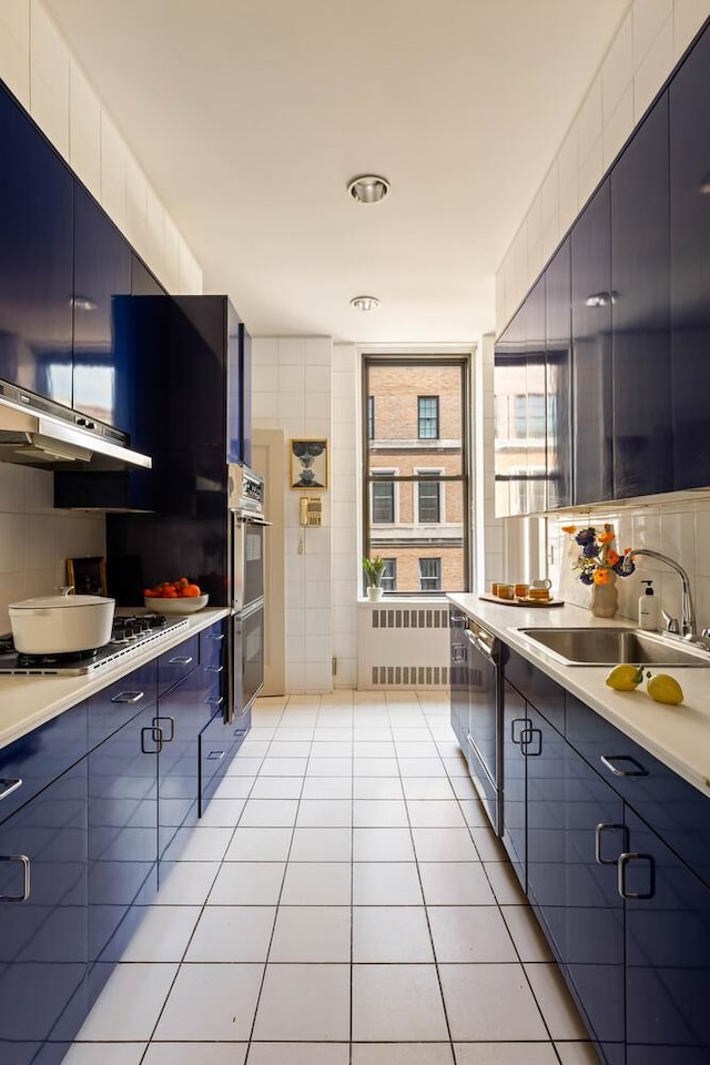993 Park Ave Unit 11A, New York City, NY 10028 - kitchen with stainless steel appliances, light tile patterned flooring, tasteful backsplash, light countertops, and blue cabinets